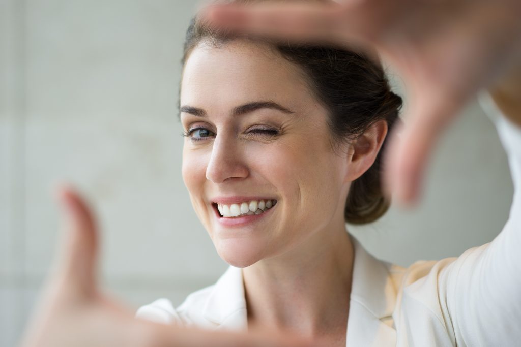 closeup of smiling woman making frame gesture