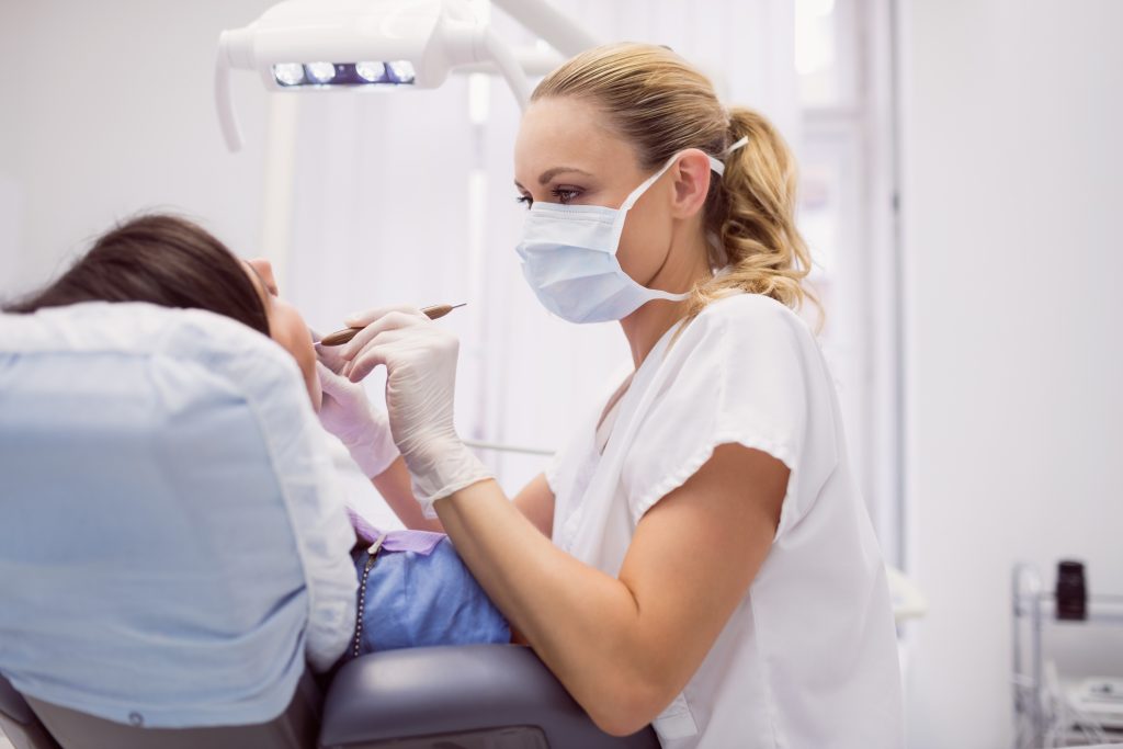 dentist examining female patient in clinic