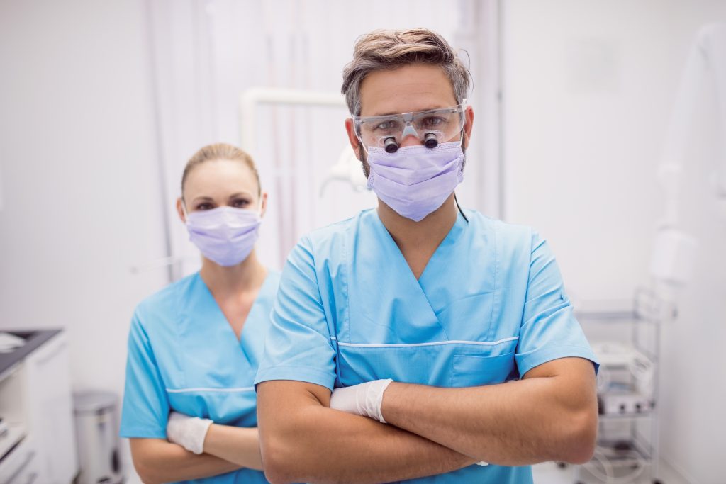portrait of dentist standing with arms crossed at dental clinic portrait of dentist standing with arms crossed at dental clinic