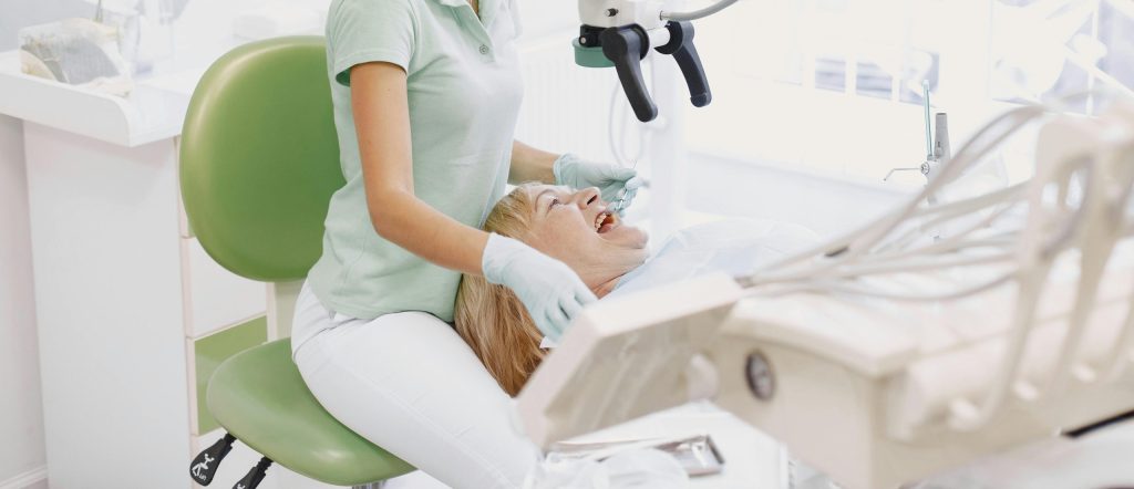 Dentist performing an examination using a microscope in a bright dental clinic.